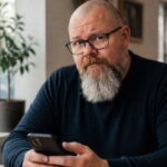 Thor Jadesø sidder på en café med telefonen i hånden og kigger skeptisk direkte i kameraet