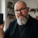 Thor Jadesø står i køkkenet, holder sin telefon op og kigger skeptisk direkte i kameraet